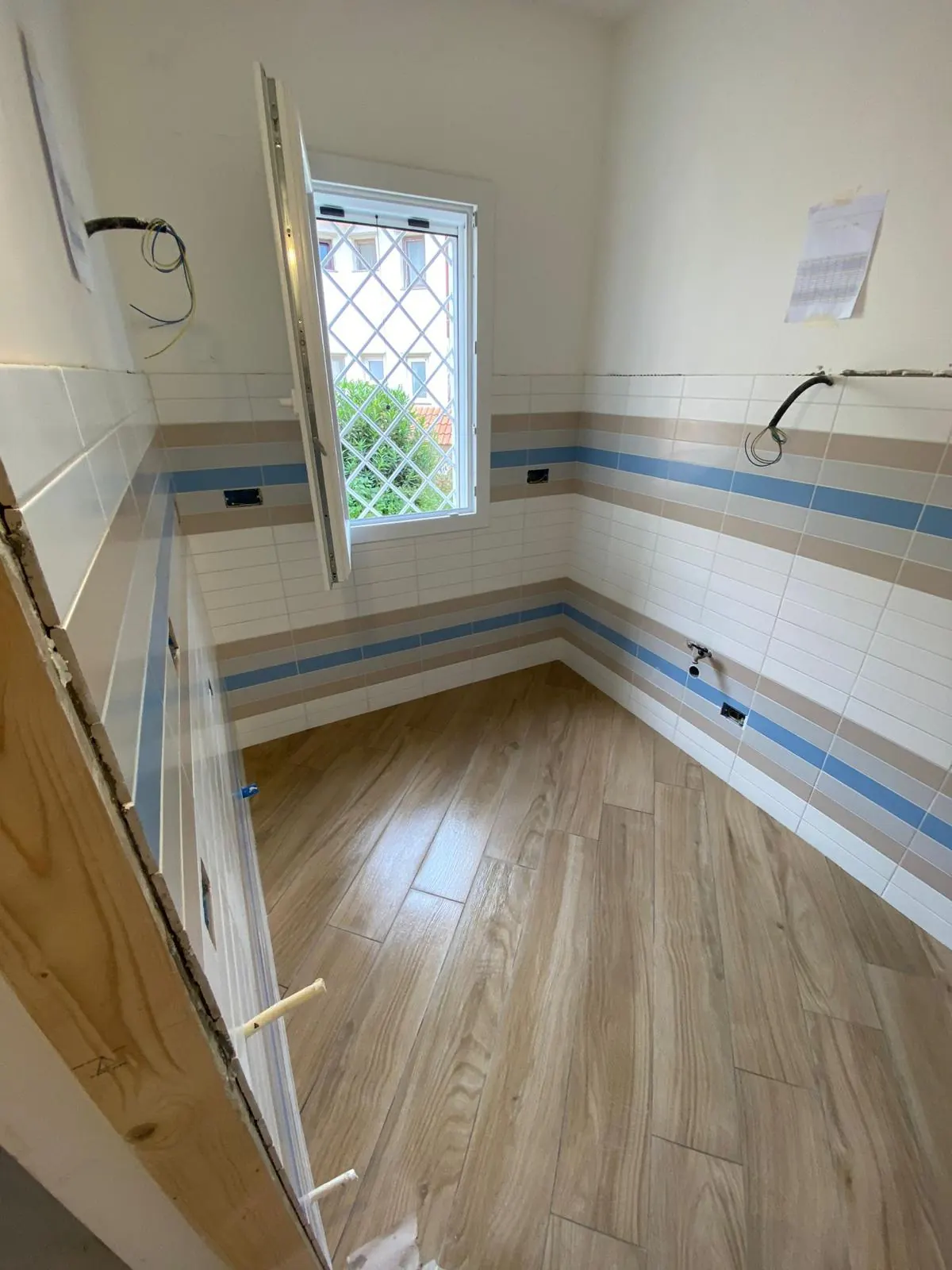 Bagno in cantiere con finestra e piastrelle a righe